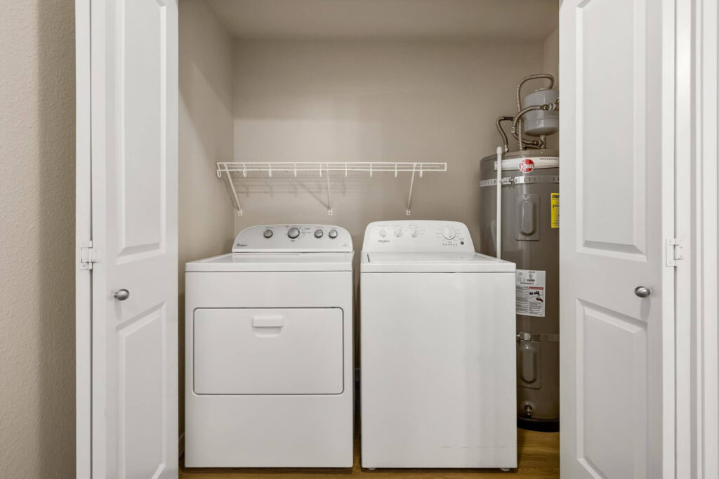 Washer and dryer next to water heater system in closet