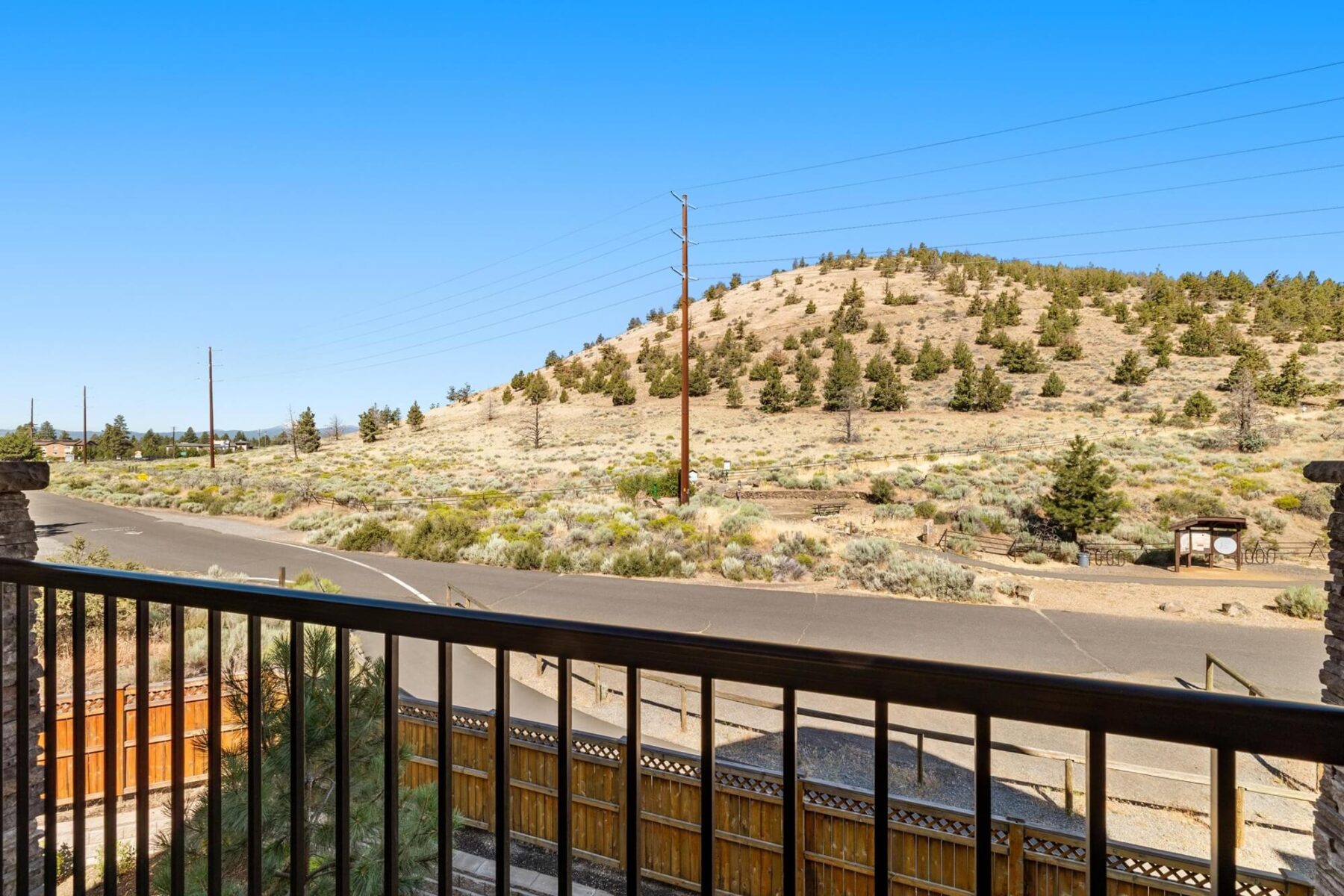 Balcony overlooking desert hill with foliage and street