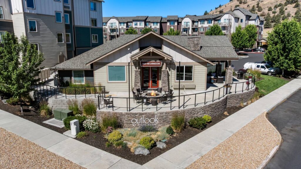 Exterior of clubhouse building, landscaping and sidewalks lining the building with apartment label signage
