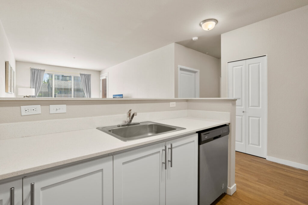 Kitchen with dishwasher, sink, and white cabinets with white countertops