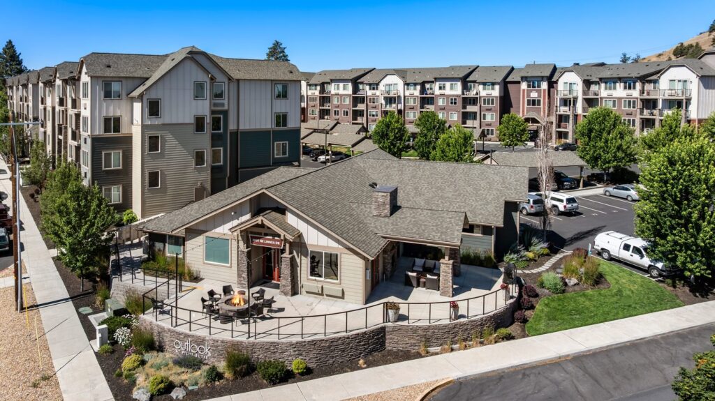 Exterior of clubhouse building, landscaping and sidewalks lining the building with apartment label signage
